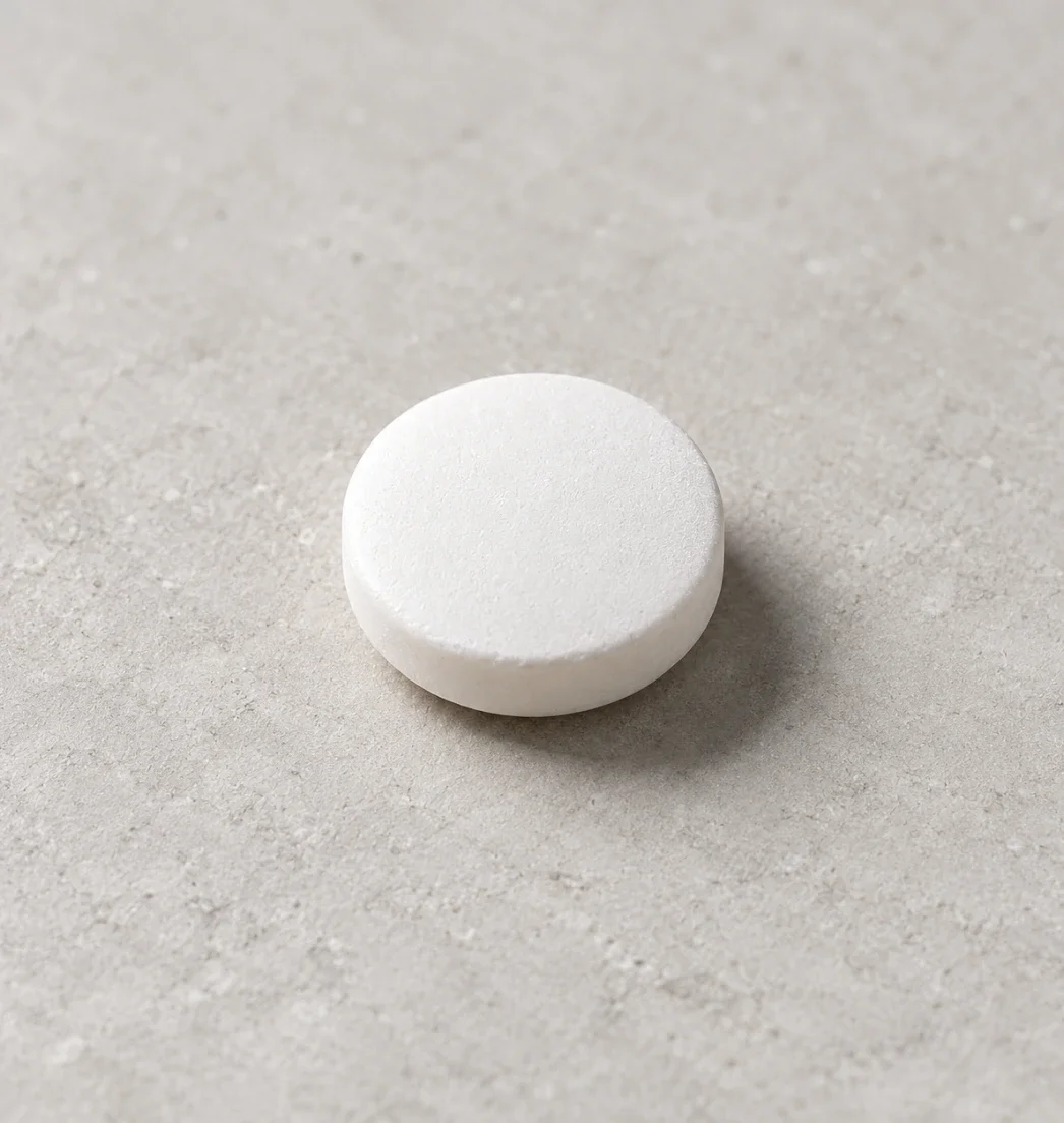 Close-up of a round white tablet on a stone surface