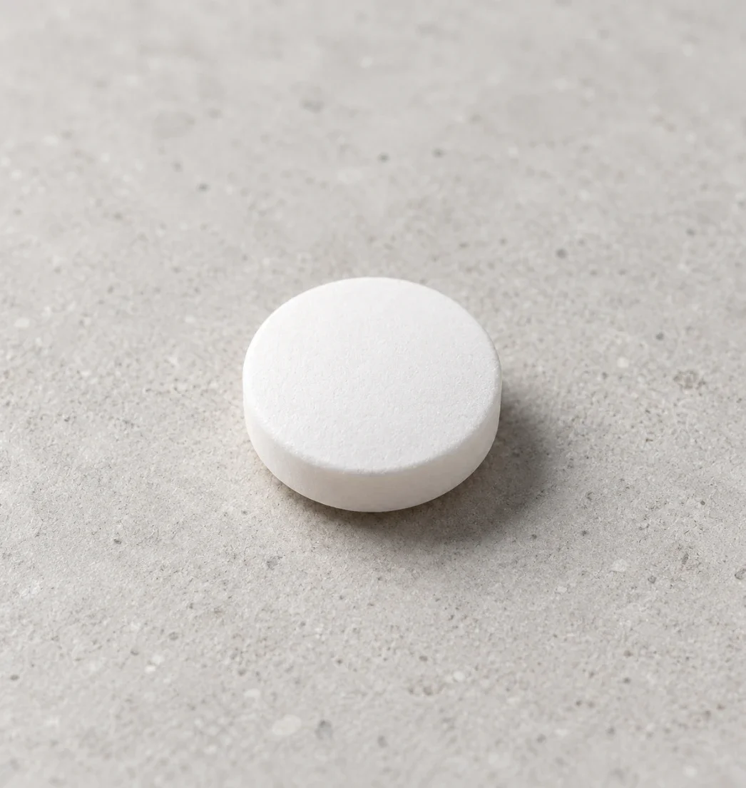 Close-up of a round white tablet on a stone surface