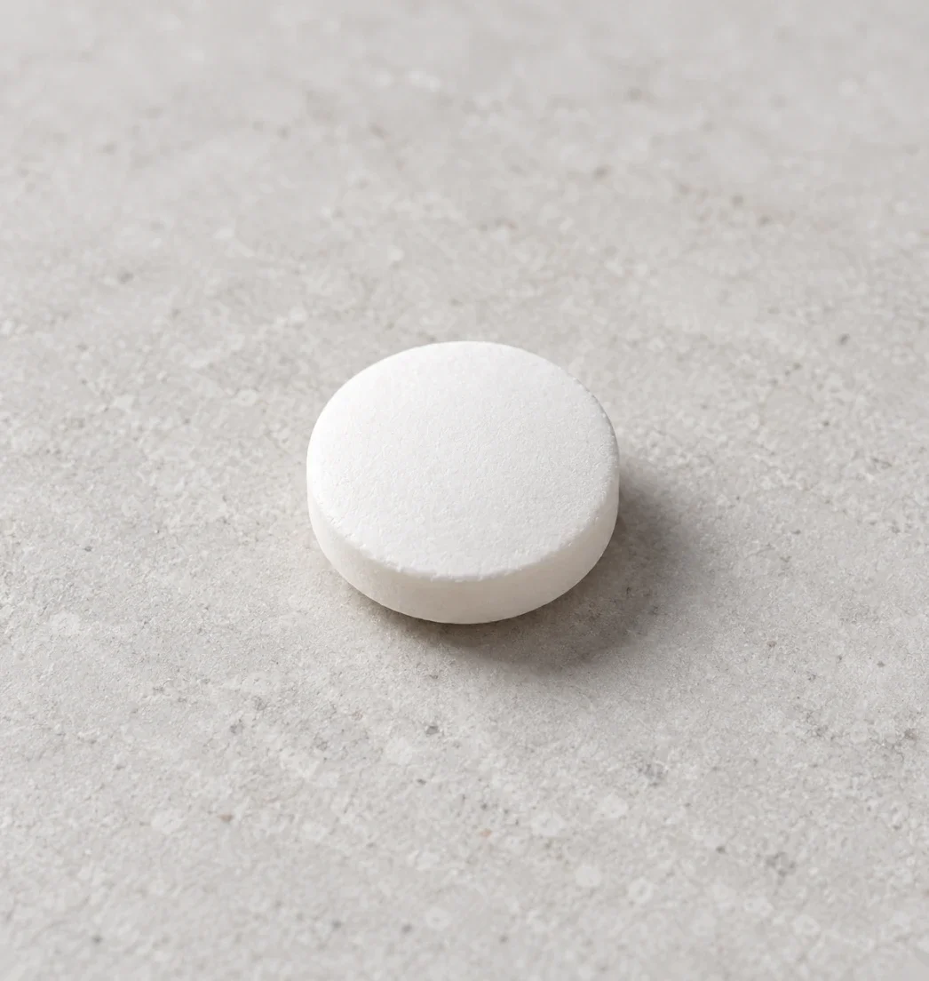Close-up of a round white tablet on a stone surface